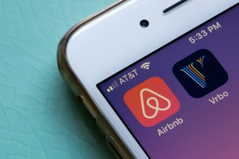 Alt text: "Close-up of a smartphone screen displaying the Airbnb and Vrbo app icons with a notification bar showing the AT&T network, Wi-Fi signal, and the time as 5:33 PM.