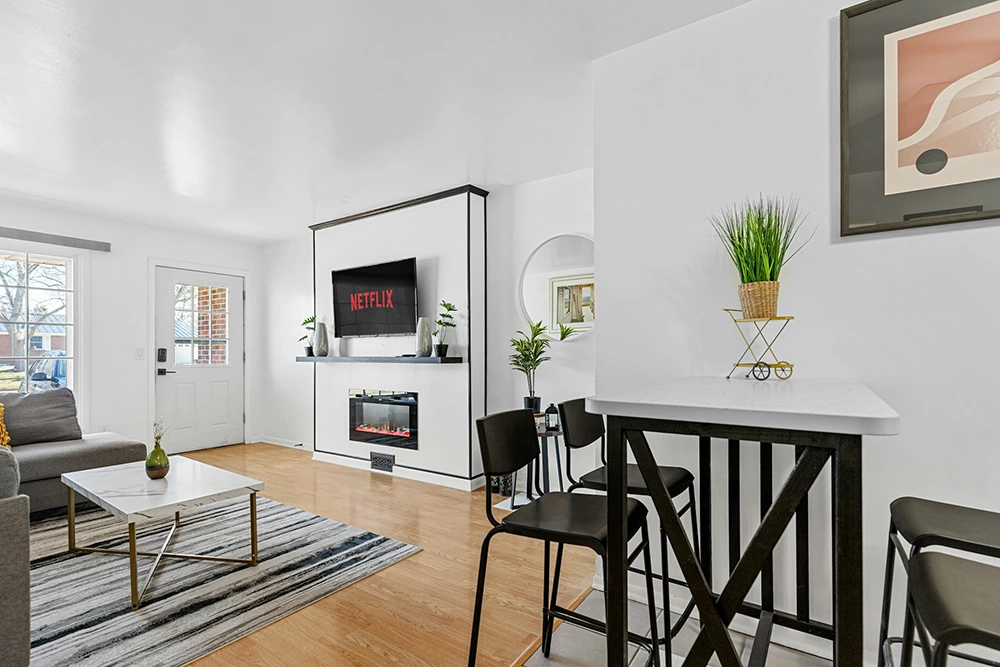 Modern living room with Netflix on TV, cozy decor, and a high dining table.